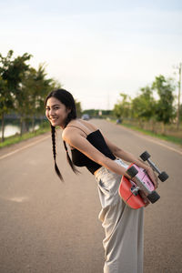 Portrait of young woman standing on street against sky