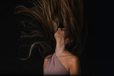 Woman tossing hair against black background