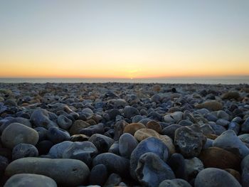 Rocks on beach against sky during sunset