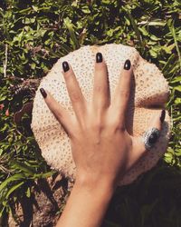 Cropped hand of woman touching mushroom on field