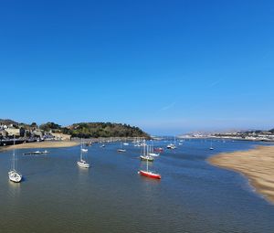 Boats in sea against clear blue sky