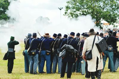 Rear view of army soldiers shooting on field