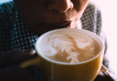 Close-up of woman drinking coffee from cup at cafe