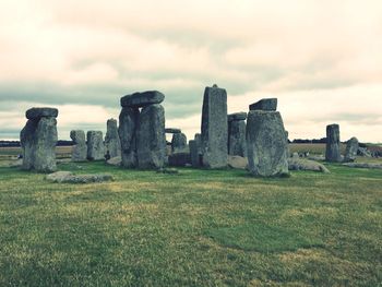 Old ruins on field against cloudy sky