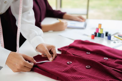 Cropped hands of fashion designer with colleague working at studio