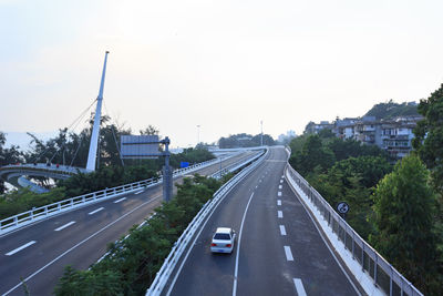 Vehicles on highway by street against sky in city