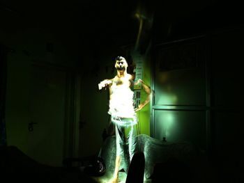 Young woman standing against illuminated wall at night