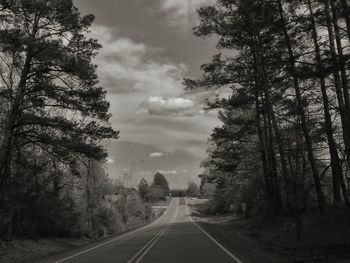 Empty straight road against cloudy sky