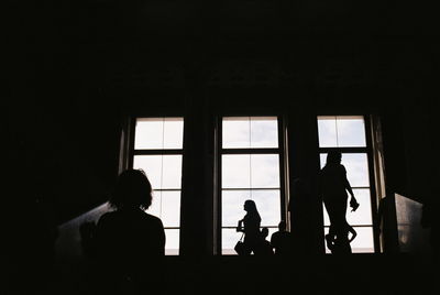 Silhouette people standing by window