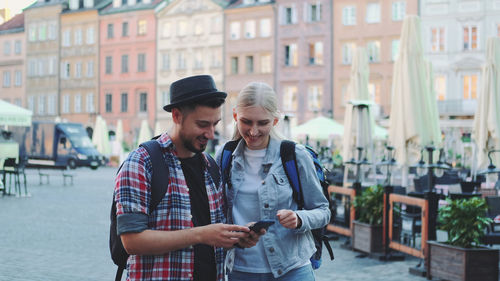 Young man using mobile phone while standing on street in city