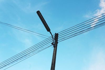 Low angle view of power lines against blue sky