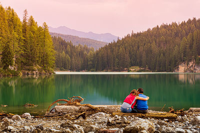 Man sitting by lake against mountains