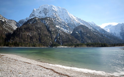 Scenic view of lake by snowcapped mountains against sky