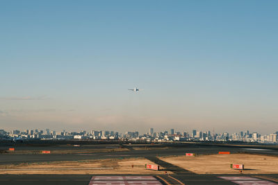 Airplane taking off over city against sky