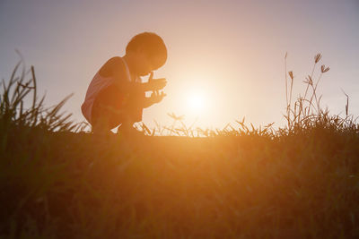 Side view of man on field against sky during sunset