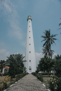 Low angle view of palm trees and lighthouse against sky