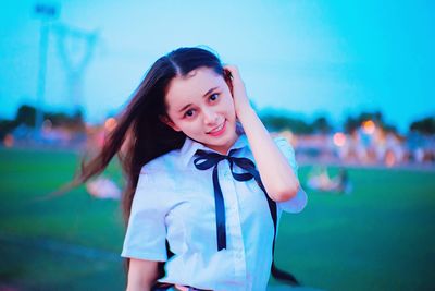 Portrait of smiling young woman standing against sky