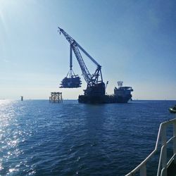 Crane on sea against clear blue sky