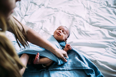 Overhead shot of newborn baby being wrapped in blanket