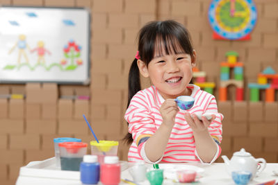 Portrait of happy girl playing with toys at home