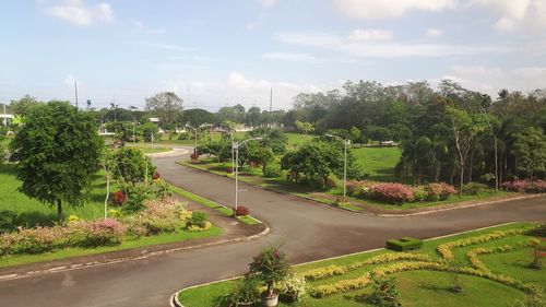 Road by trees in city against sky