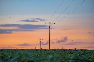 Electricity pylon on field against sky during sunset