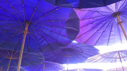 Low angle view of umbrellas hanging against blue sky