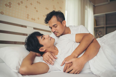 Loving gay couple lying on bed at home