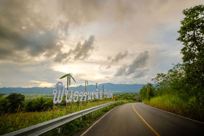 Empty road amidst plants against sky