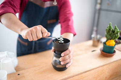 Midsection of man holding coffee cup on table