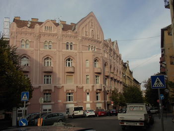 Traffic on road by buildings in city against sky