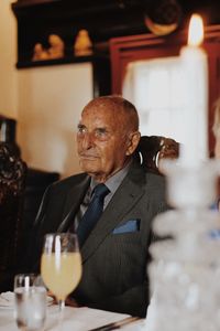 Portrait of man with drink sitting in kitchen