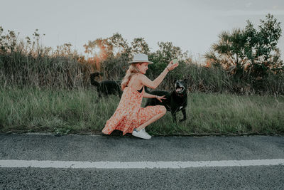 Woman with umbrella on road against sky