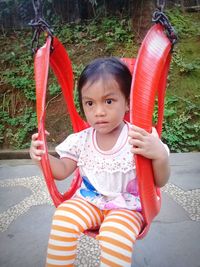 Thoughtful girl sitting on swing at playground