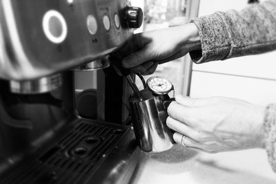 Cropped of hand preparing latte coffee, brewing machine , foaming , vintage black and white tone. 