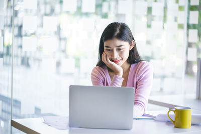 Portrait of woman using phone while sitting on table