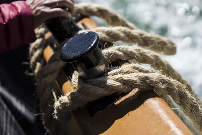 Close-up of hand holding rope tied to metal