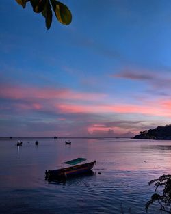 Boat moored in sea against sky during sunset