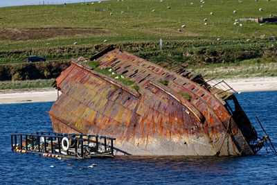 Abandoned boat moored on sea shore