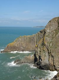 Scenic view of rocks by sea against sky
