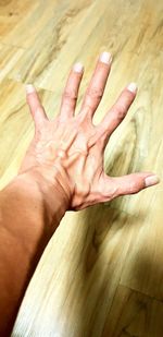 High angle view of human hand on hardwood floor