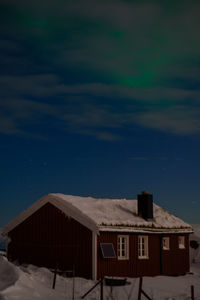 Houses by building against sky at night during winter