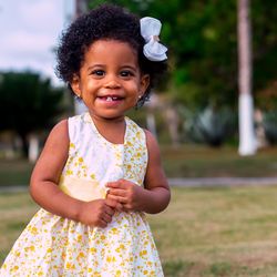 Portrait of smiling baby girl standing on field