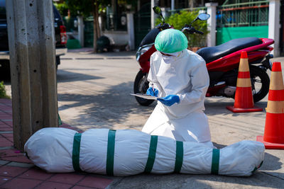 Man holding umbrella on footpath in city