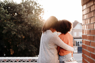 Mother and daughter sitting together on terrace at sunset