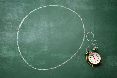 Directly above shot of alarm clock with speech bubble on blackboard