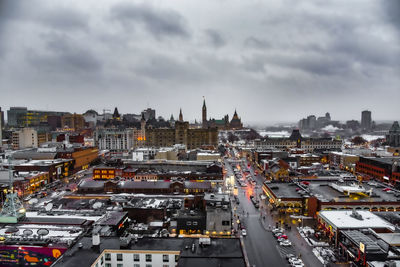 High angle view of city buildings against cloudy sky