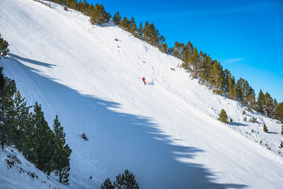 Skiers skiing down the steep piste in pyrenees mountains, andorra