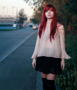Beautiful young woman standing against red wall