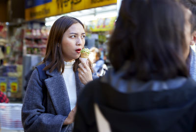 Close-up of woman eating ice cream standing on street